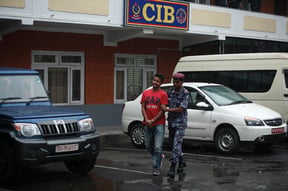 A Nepal Police officer escorts co-pilot of Goma Airlines Bishal Karki, 36, to a press conference held in Central Investigation Bureau in Maharajgunj on Wednesday. He was arrested for submitting fake academic credentials earlier this week.