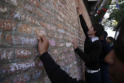 PRAYERS FOR PEACE: Students write on a wall near the Saraswati Temple in Swayambhu Nath Temple area on Tuesday in celebration of Shree Panchami, the festival when Saraswati, the goddess of knowledge, is worshipped.