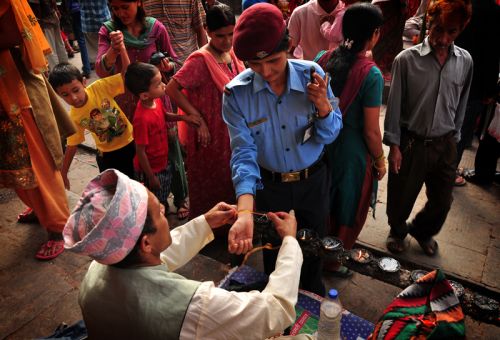 SACRED THREADS : A hindu priest ties a holy threads to police woman during the Janai Purnima festival at Bagalamukhi temple in Lalitpur on Saturday.