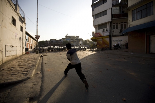 A protestor throws a brick at armed police force members when demonstrations outside the royal palace turned violent.