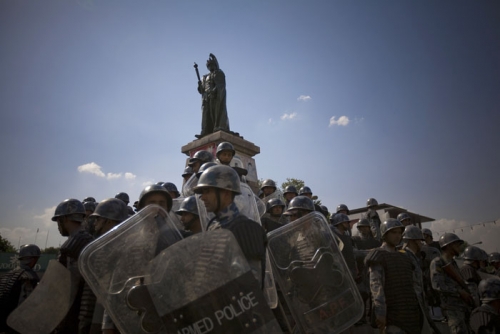 Armed Police Force members surround the statue of King Birendra as angry crowds threaten to deface it in an attempt to demand the immediate evacuation of the royal family from the palace.
