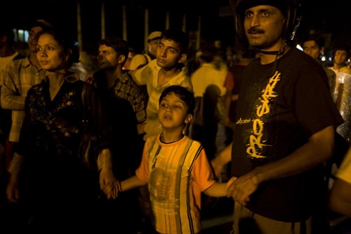 A family looks on eagerly as the state flag is hoisted at the royal palace Thursday night.