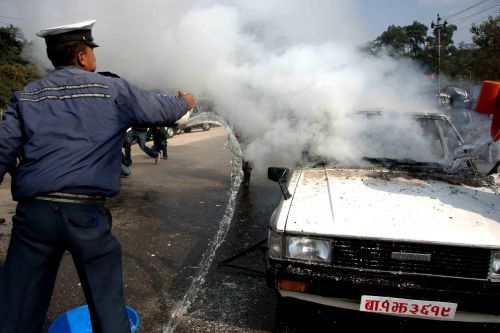 DAMAGE CONTROL: A traffic police tries to control fire on a government vehicle, set by members of Youth Association Nepal (YAN), a sister wing of the CPN-UML, in Kathmandu on Sunday. They were protesting against misappropriation of the Self-Employment Fund.