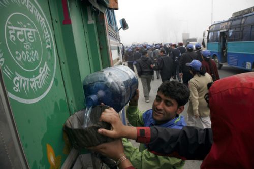 RISKY REPLACEMENT: Faced by petrol shortage, a truck driver and his conductor pour kerosene into the fuel tank instead in urgency to move the vehicle stuck on the main road.