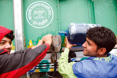 RISKY REPLACEMENT: Faced by petrol shortage, a truck driver and his conductor pour kerosene into the fuel tank in urgency to move the truck stuck on the main road at Gaushala on Tuesday.