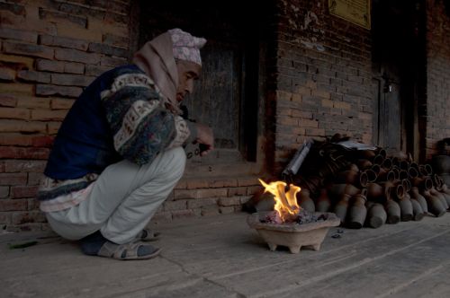 WARM FLAMES: A local potter fights the evening cold with a small fire in Bhaktapur on Sunday.