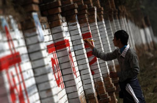 WRITING ON THE WALL: A young painter paints political slogans on a wall in Boudha last week.