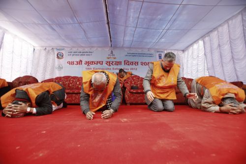 DUCK! PM Baburam Bhattarai follows the duck, cover and hold rule at an earthquake drill during a program to mark the 14th Earthquake Day in Jawlakhel on Monday.