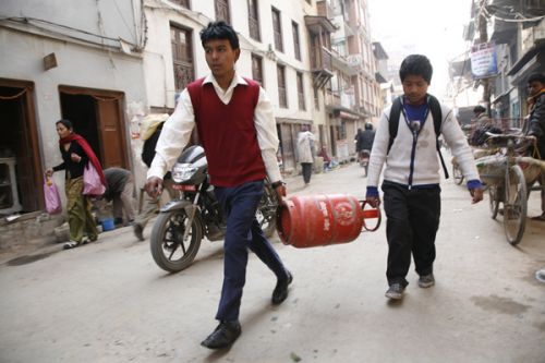 EMPTY JAR: A student helps his friend carry an empty cylinder to a gas depot in Naradevi, Kathmandu on Wednesday morning.