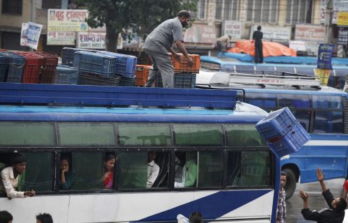 CATCH! A worker loads cargo on a bus at the station in Kalanki on Tuesday evening.