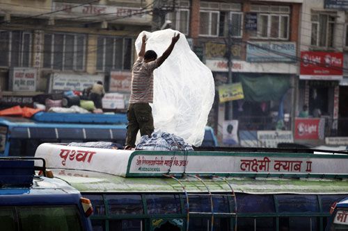 WATER PROOF: A conductor spreads plastic on cargo on a passenger bus in Kalanki station, Kathmandu, on Tuesday evening after a sudden rainfall.