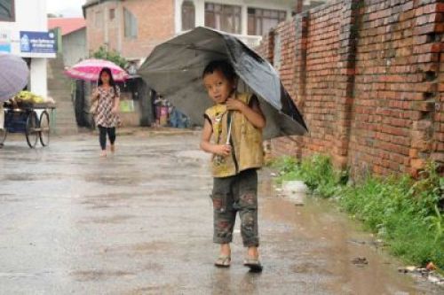 UNDER MY UMBRELLA: A boy enjoys a light afternoon drizzle on Monday in Teku.PIC