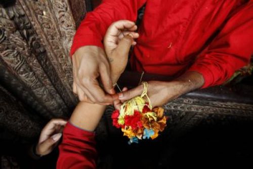 HOLY THREAD : A priest at the Baglamukhi temple in Patan ties a sacred thread on Janai Purnima, Thursday morning PIC