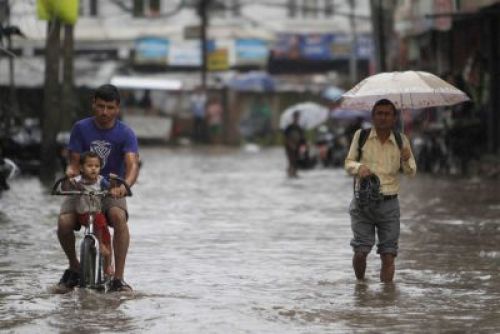 RAINY TRIATHLON: A man tries to cycle, while another struggles to walk through water-clogged streets in Nayabazaar after heavy downpour on Sunday afternoon.