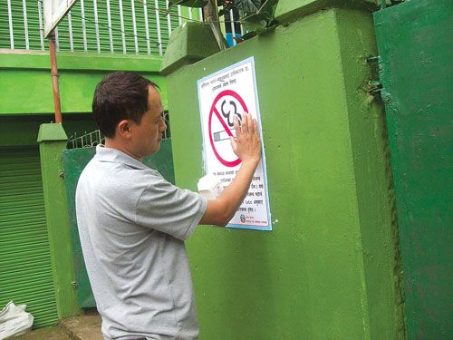 NO SMOKING PLEASE: A member of Hotel Association of Ilam pastes a no smoking sticker at Ilam Municipality's gate on Wednesday.