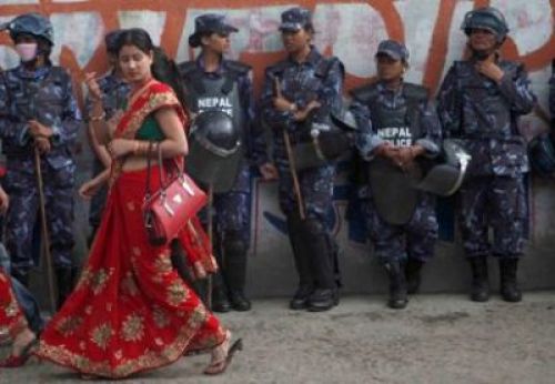 DIFFERENT DRESS CODES: Police women on duty look on as a woman dressed in bright red sari passes by after atttending a Teej program on Monday. PIC