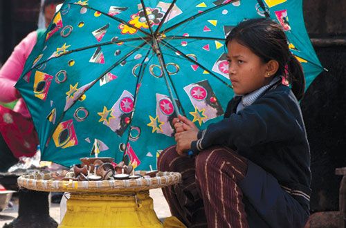 READER'S PHOTO: Instead of playing with her friends, a schoolgirl helps her family sell oil lamps in front of Swayambhunath stupa.