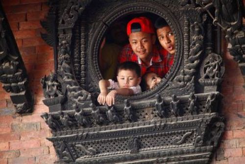 OUR TURN: Children look out through a window in Kumari Ghar as the Kumari is taken on a chariot procession through Basantapur on Saturday. PIC