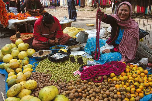 ADDED VALUE: A woman offers Bachelor Buttons garlands which are used during Bhai Tika on Thursday at her fruit stall in Kathmandu Darbar square.