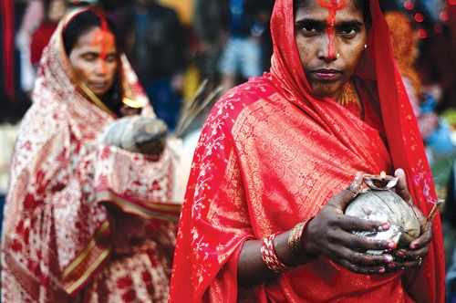 SHINE ON: Devotees offer coconuts and light oil lamps in honour of the sun god, Surya, during Chhath puja in Rani Pokhari on Monday.