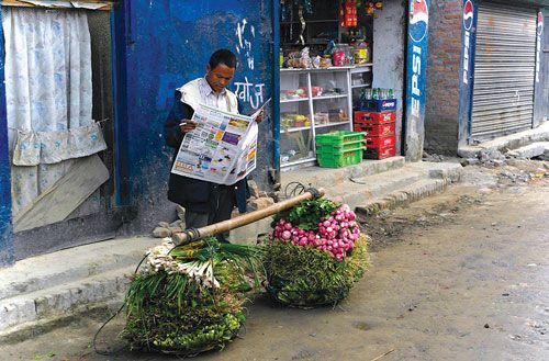 RIGHT TO READ : A vegetable vendor leaves his morning duties for a while to read the daily newspaper near Kamal Pokhari.
