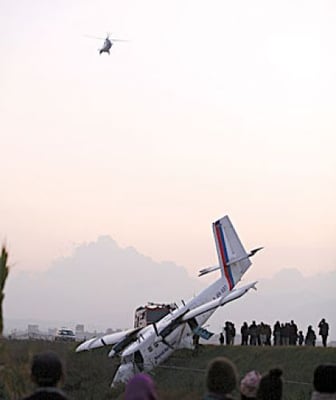 CRASH LAND: This Nepal Airlines Twin Otter crashed during a training flight on Wednesday injuring two, while a helicopter bringing back Prime Minister Pushpa Kamal Dahal from Butwal prepares to land.