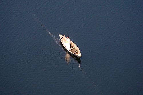CALM WATERS: A fisherman ferries his boat across the Kulekhani reservoir on Saturday.