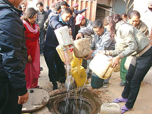 DOWN THE HATCH: Locals dispose of illegal homemade alcohol with the help of Lagankhel police on Saturday.