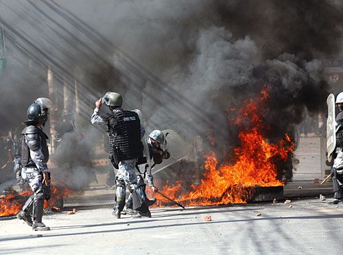 CHAOS: A fire rages as police stand guard in New Baneswor following riots during the Maoist-called Nepal Bandh on Sunday.
