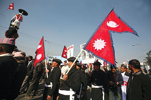 HISTORY: Men dressed in traditional military attire hold up the national flag beneath a statue of Prithvi Narayan Shah in front of Singh Darbar on his birth anniversary, Monday.