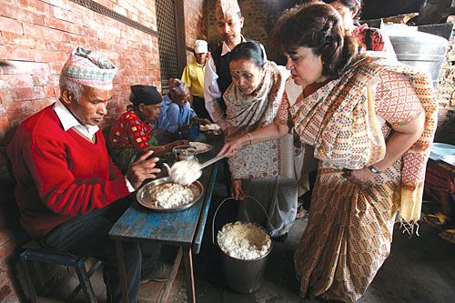 GRAINS OF HOPE: Deputy Prime Minister and Foreign Minister Sujata Koirala, whose father passed away recently, serves rice to seniors at an old age home in Pashupati on Wednesday, as is customary on the 12th day of mourning.