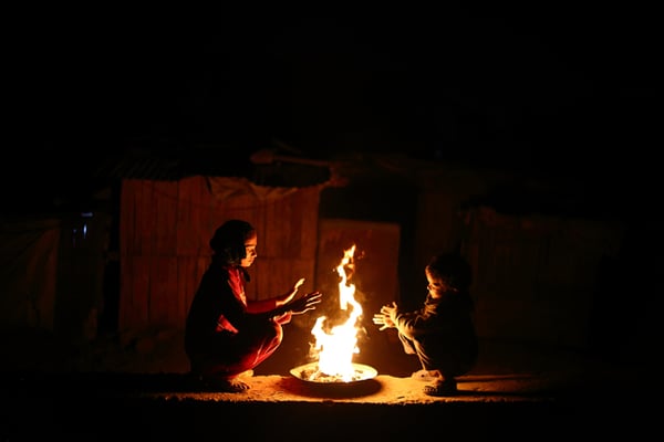 Children huddle beside a fire to keep themselves warm at Teku on Thursday.