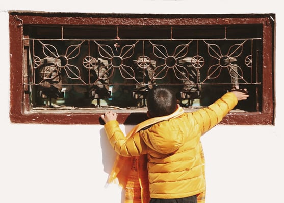 A young boy spins prayer wheels at Boudhanath Stupa on Saturday.