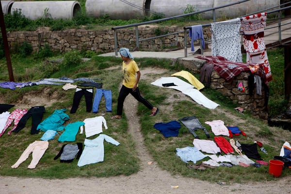 A woman dries her clothes on the ground near Godawari River at Tikathali on Tuesday.