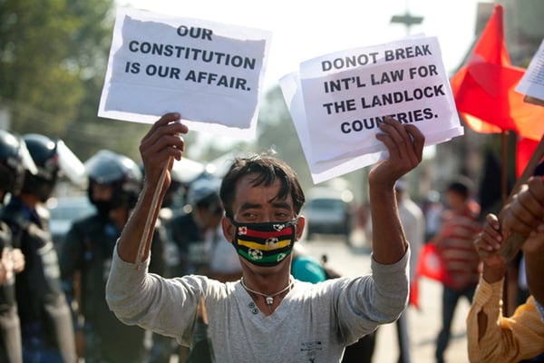 A protester carries placards denouncing the unofficial economic blockade imposed by India at Lainchaur on Wednesday.