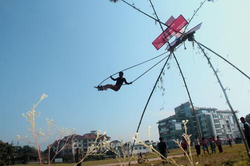 Children line up for their turn to play with a swing in a field in Naxal on Thursday.