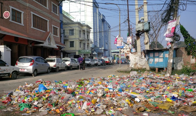 Petrol queue snakes past garbage piling up in Kathmandu a month since the Indian blockade at Patan Dhoka on Wednesday.