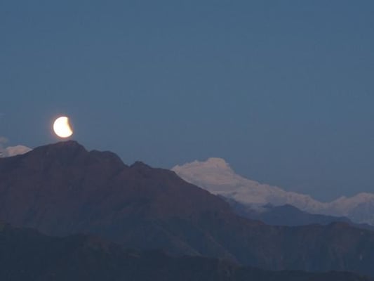 Mt Himalchuli turns pink in the setting sun, as a partially eclipsed moon rises on Wednesday over central Nepal.