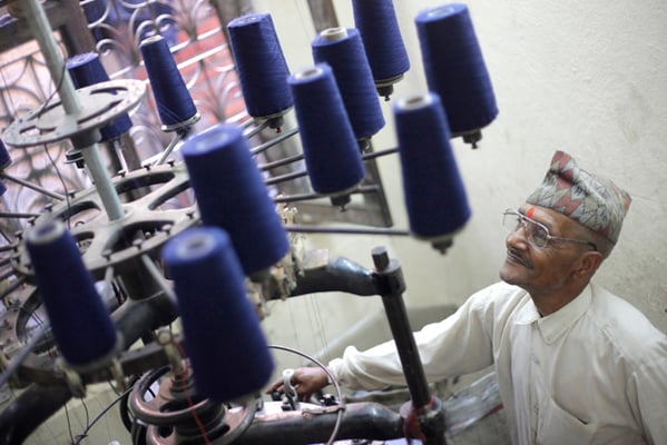 60-year-old Keshav Prasad Kandel from Nuwakot operates a knitting machine which produces woolen caps at Om Bahal on Wednesday.