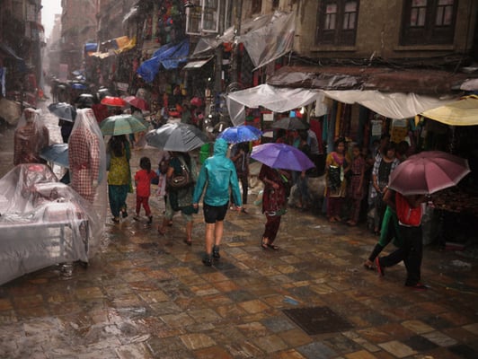 People walk in the rain through a busy street near Kel Tole on Sunday.