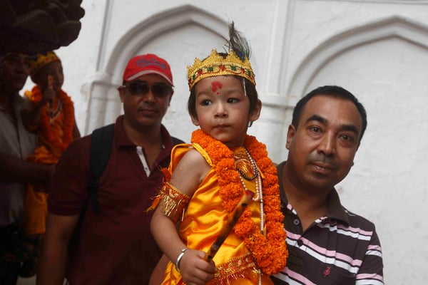 A man carries his child dressed as the Hindu god Krishna during Gai Jatra in Kathmandu on Monday.