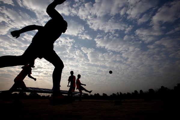 A group of boys play football at the break of day in Tundikhel ground on Monday.