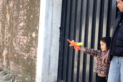 YES, I CAN: A little girl plays with her dad to shoot passerbys with a water pistol toy in Ekantakuna on Tuesday.