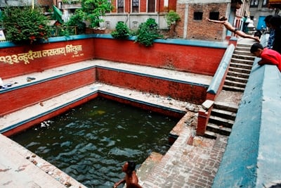 GOING FOR A DIVE: Children play in a man made pond filled with rainwater in Natole, Patan, on Thursday.