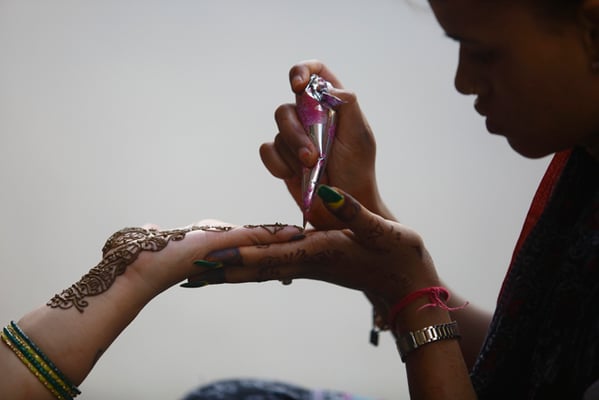 16-year-old Jyoti Baniya of Jitpur, Bara applies henna for her customer on the first day of the Nepali month Shrawan in New Road on Sunday.