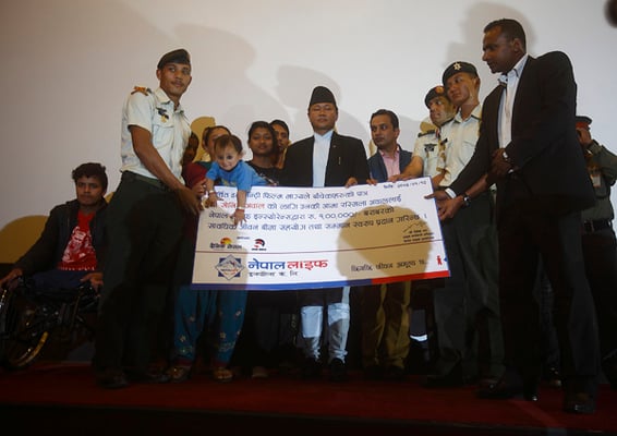 Rashmila Awal, the mother of 17-month-old Sonish Awal who was rescued alive after being buried for 22 hours in last year's earthquake, receives an insurance worth Rs 100,000 for his son in Kathmandu on Sunday.