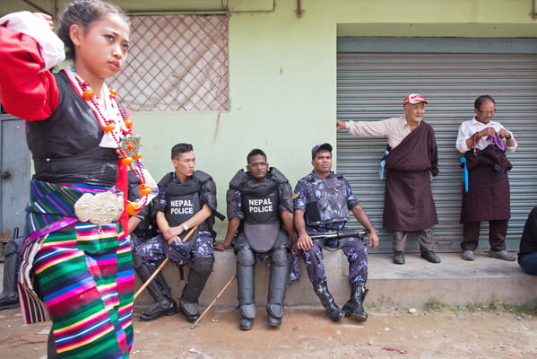 A Tibetan woman walks past a group of policemen at the refugee camp, where hundreds of Tibetans gathered to celebrate their spiritual leader Dalai Lama's 79th birthday on Sunday.
