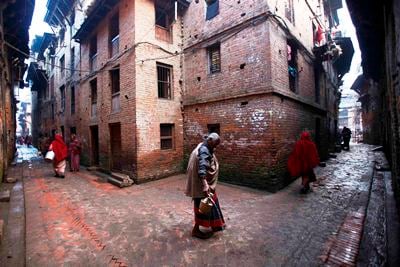 ON THE WAY: An old woman sprinkles water on the pavement while heading for early morning prayer at a temple in Bhaktapur on Saturday.