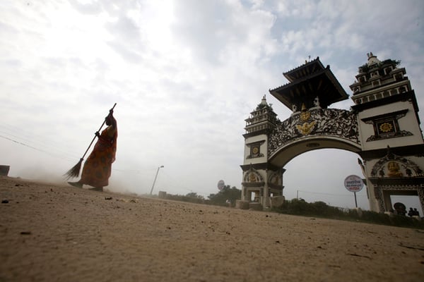 A woman sweeps the dust off the road near the border between Nepal and India in Birgunj on Sunday. The border has been blocked since the promulgation of the new constitution and protests by the Madhesi parties have continued.