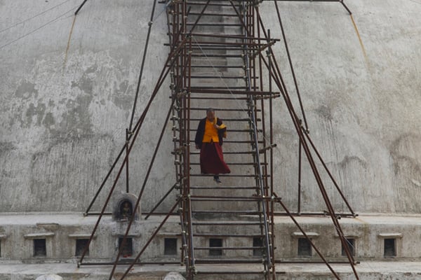 A monk climbs down a temporary ladder used for reconstruction of the Boudhanath Stupa in Kathmandu on Wednesday. It is one of the many heritage sites damaged during the April 2015 earthquake in Kathmandu.